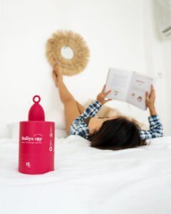 Haliya Cup menstrual cup creative shot with woman comfortably resting on her back and white sheets